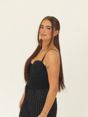 Woman wearing a black top and striped pants against a plain background