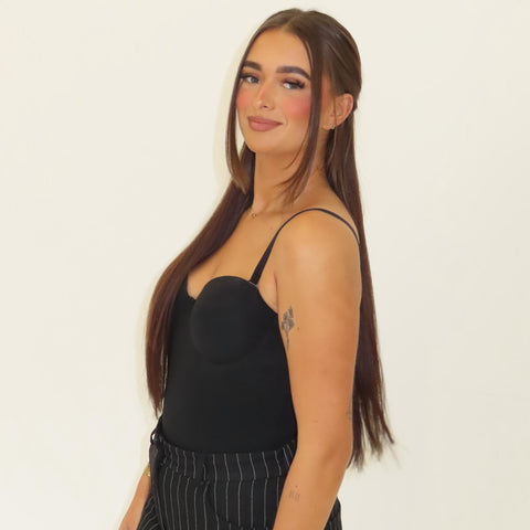 Woman wearing a black top and striped pants against a plain background