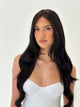 Woman with long black hair wearing a white top on a plain background