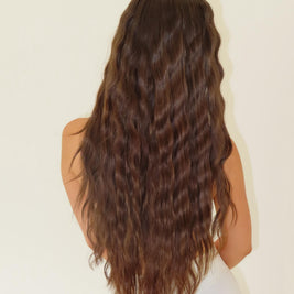 Person with long, wavy brown hair on a plain background