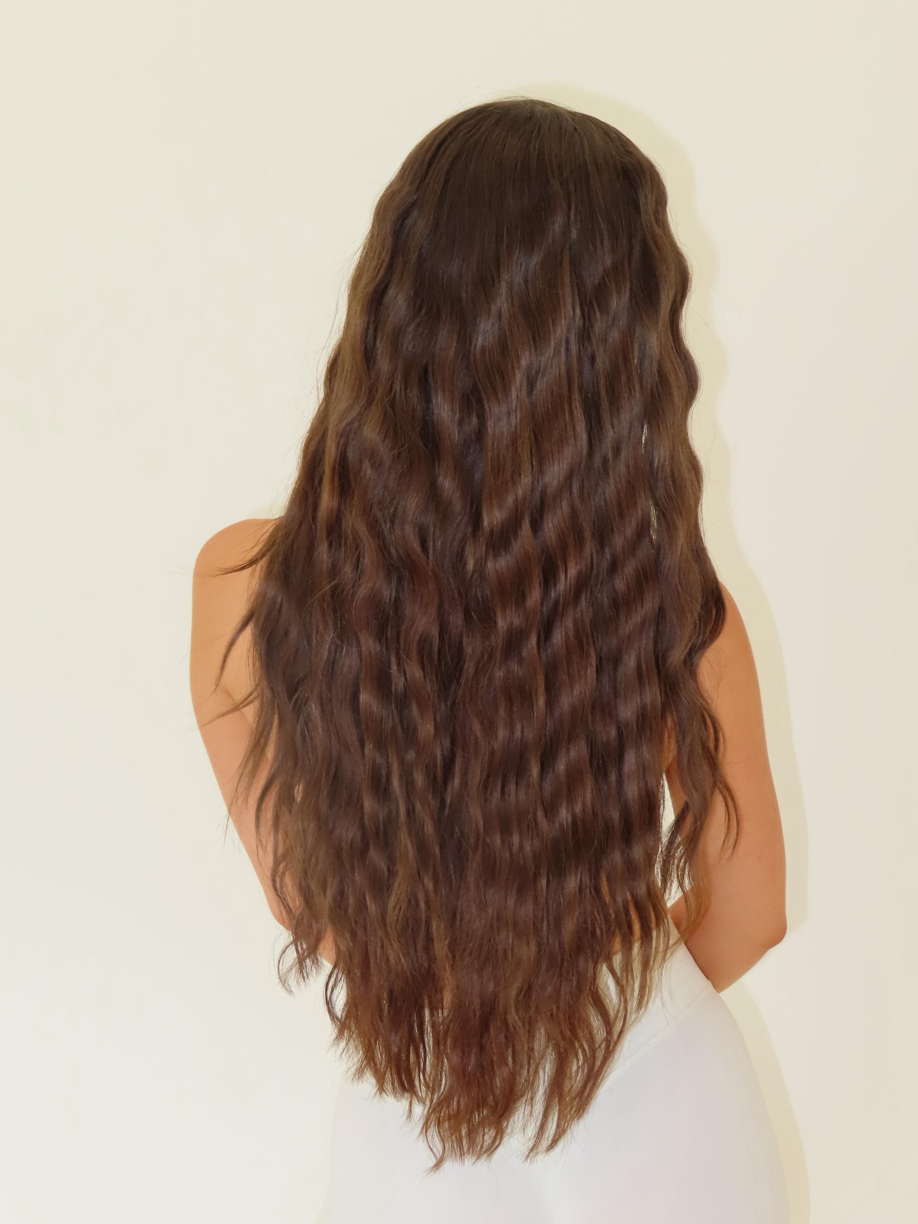 Person with long, wavy brown hair on a plain background