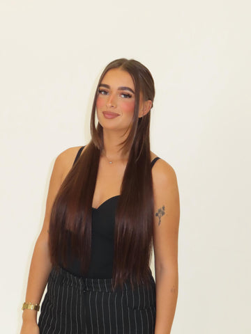 Woman with long straight hair wearing a black top against a plain background