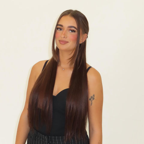 Woman with long straight hair wearing a black top against a plain background